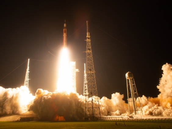A rocket launches from Earth against a night sky