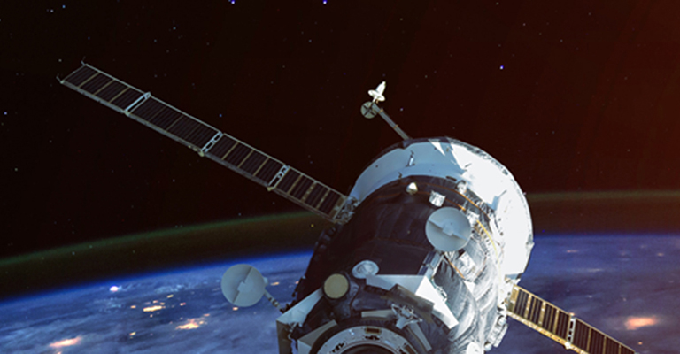 A satellite seen from space with Earth below it and the moon in the distance